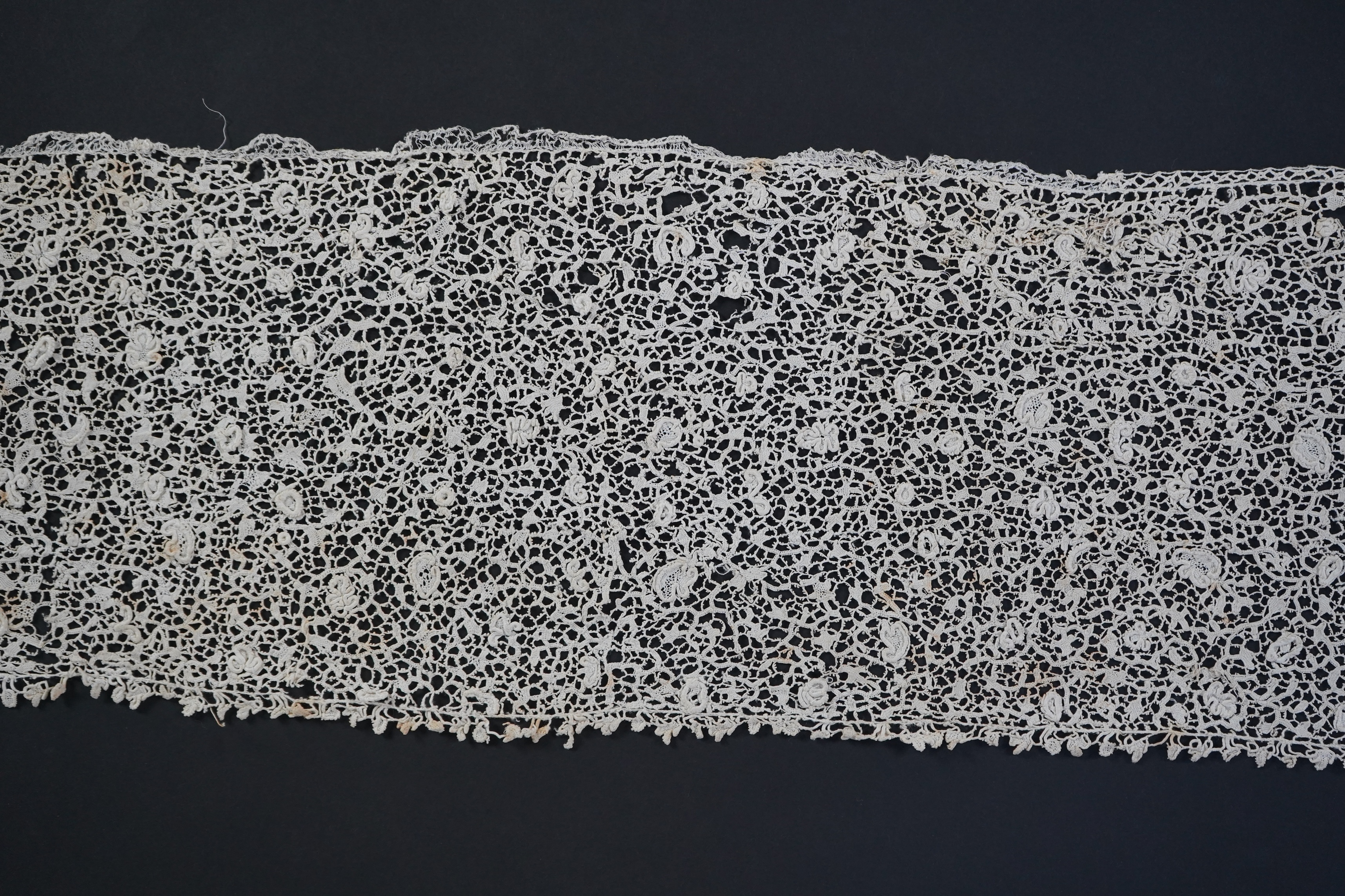 A late 17th century wide flounce of Point de France needle lace, together with a narrower flounce, both with raised elements of the design in the style of Point de Rose, but less so. This lace was very popular with the F